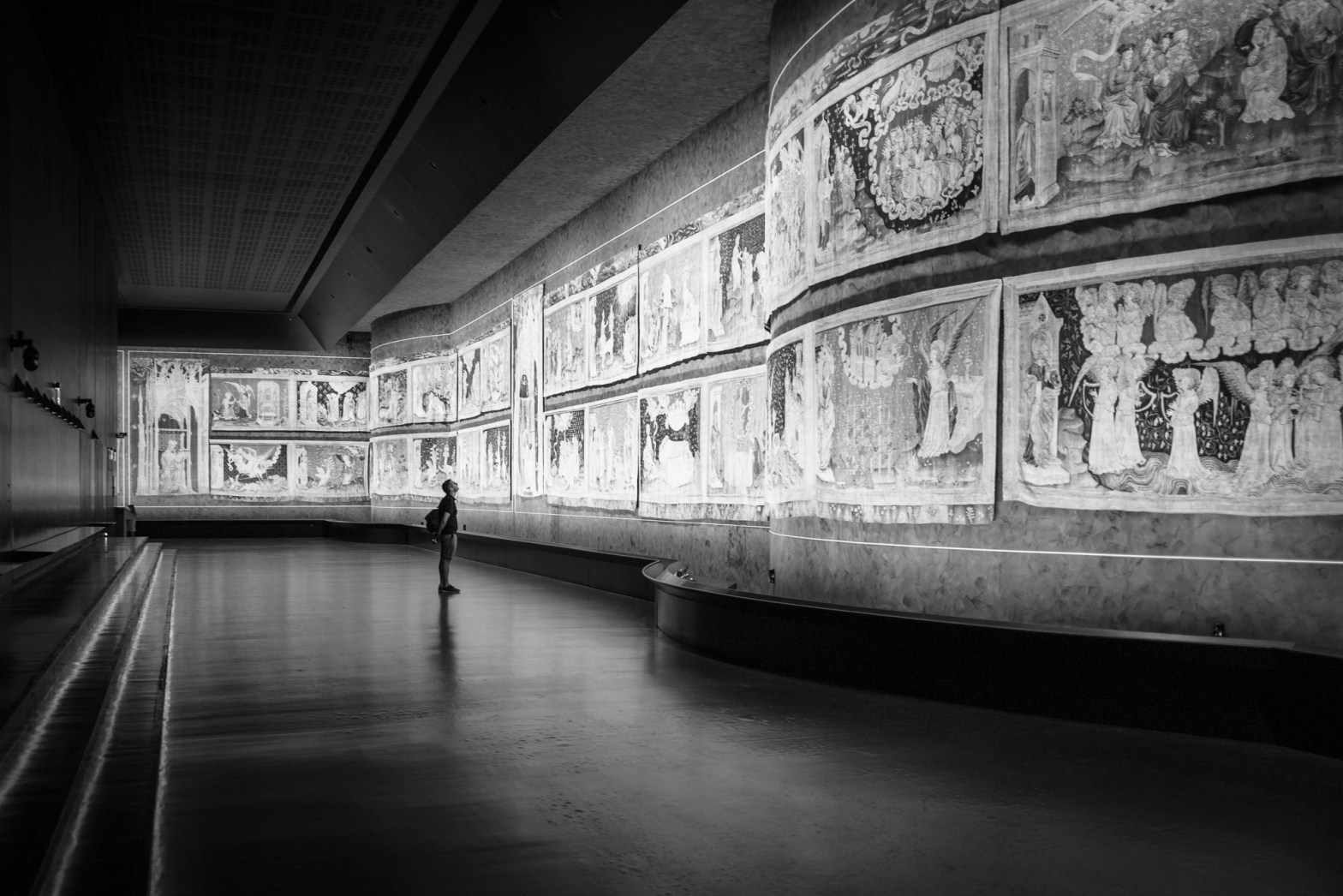 A white man stands looking up at the apocalypse tapestry